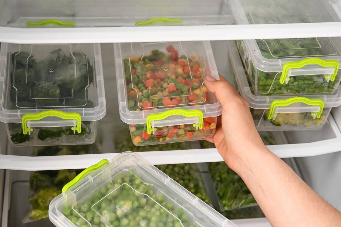 Woman Putting Containers with Vegetables in Refrigerator